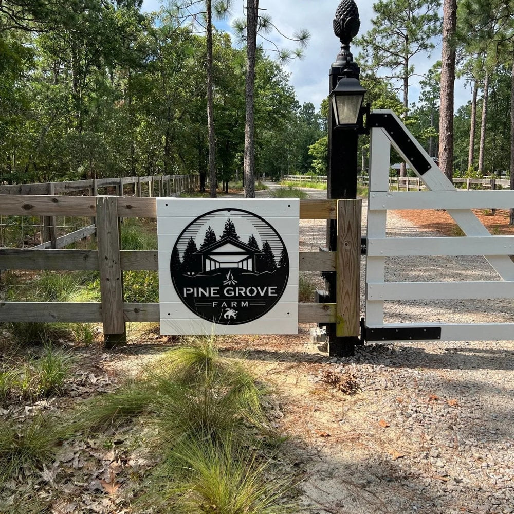 Custom metal office and storefront sign featuring laser-cut “Pine Grove Farm” logo mounted on a white gate, decorative steel signage in a forested setting.