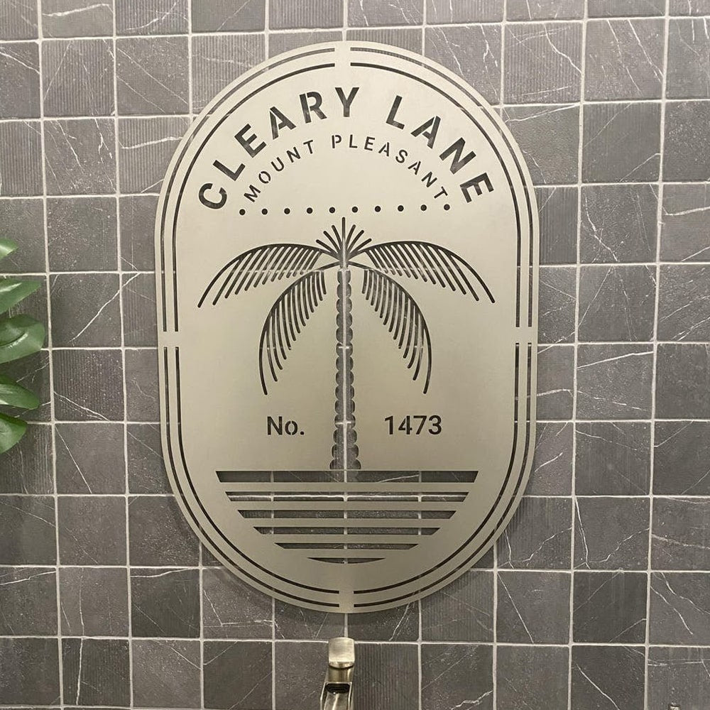 Custom metal office and storefront sign with laser-cut “Cleary Lane” logo and palm tree design, decorative steel wall art on tiled background.