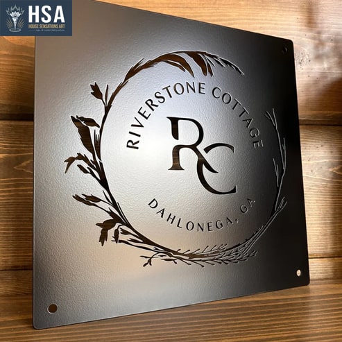 Metal sign with 'Riverstone Cottage' logo on a wooden background