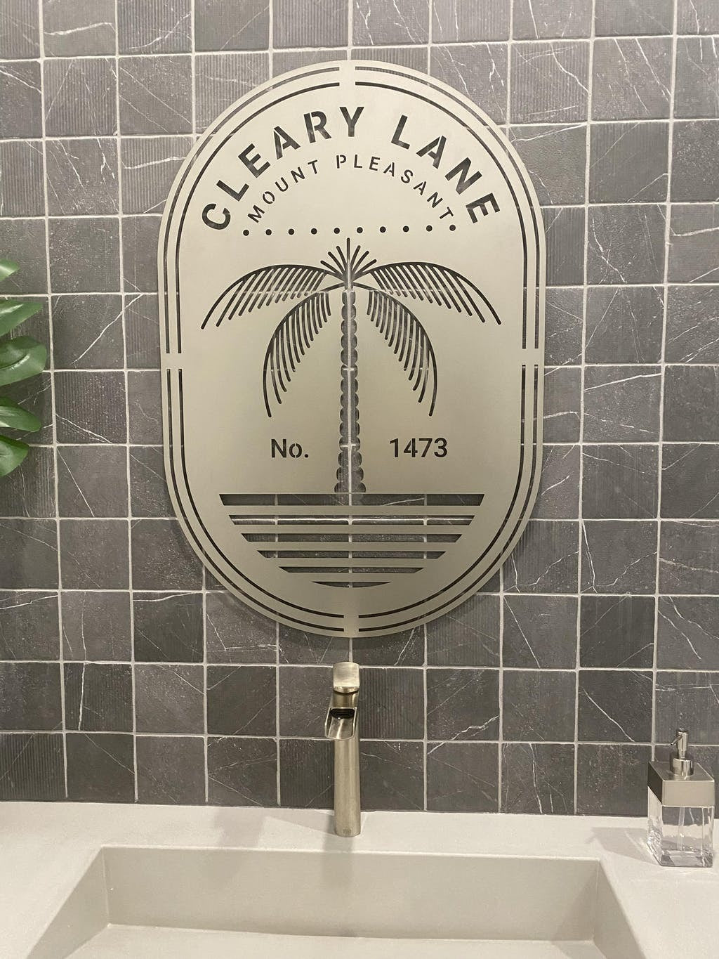 Oval steel sign with bold “CLEARY LANE,” palm tree graphic, and “MOUNT PLEASANT” and “No. 1473” below.