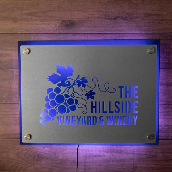 Decorative metal sign for “The Hillside Vineyard & Winery” featuring a grapes and vine design, displayed on a wooden background, showcasing rustic charm and elegant craftsmanship.