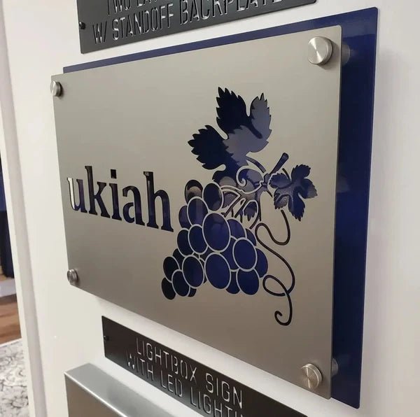 Metal sign featuring the text “ukiah” with a grape design, displayed on a white background, highlighting vibrant colors and durable craftsmanship.