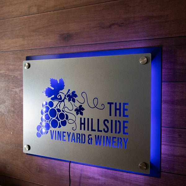 Metal sign featuring “The Hillside Vineyard & Winery” logo displayed on a wooden background, highlighting rustic design and durable metal craftsmanship.