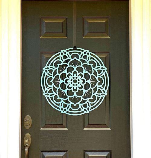 Decorative mandala wall art displayed on a dark green front door, featuring an intricate lotus-inspired design and durable metal craftsmanship for stylish outdoor décor.