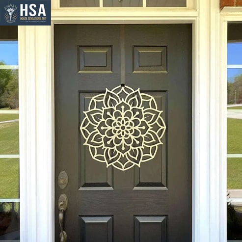 A metal wreath with a lotus design being hanged in front of the door.