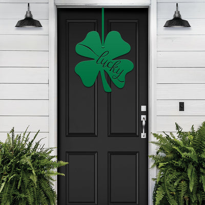 Lucky Shamrocks metal door wreath with green four-leaf clover design and “Lucky” text on black door, festive Irish home décor with greenery.