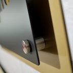 Close-up of a metal business logo mounted on a wall, showing the mounting details with a blurred background, highlighting durable construction and professional design.