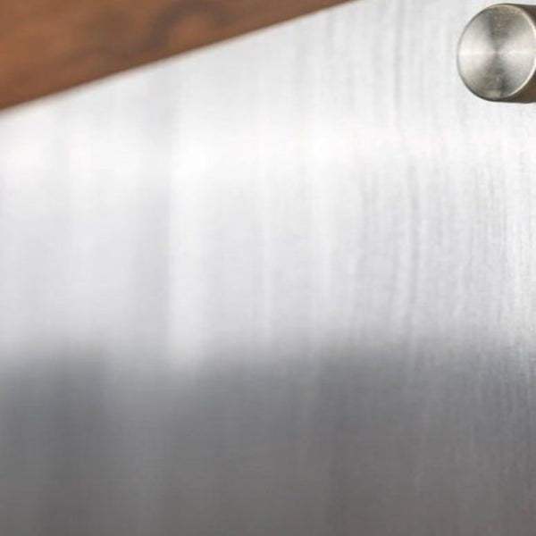 Close-up of metallic surface with knob on wooden background, House Sensations Art branding, decorative metal finish sample.