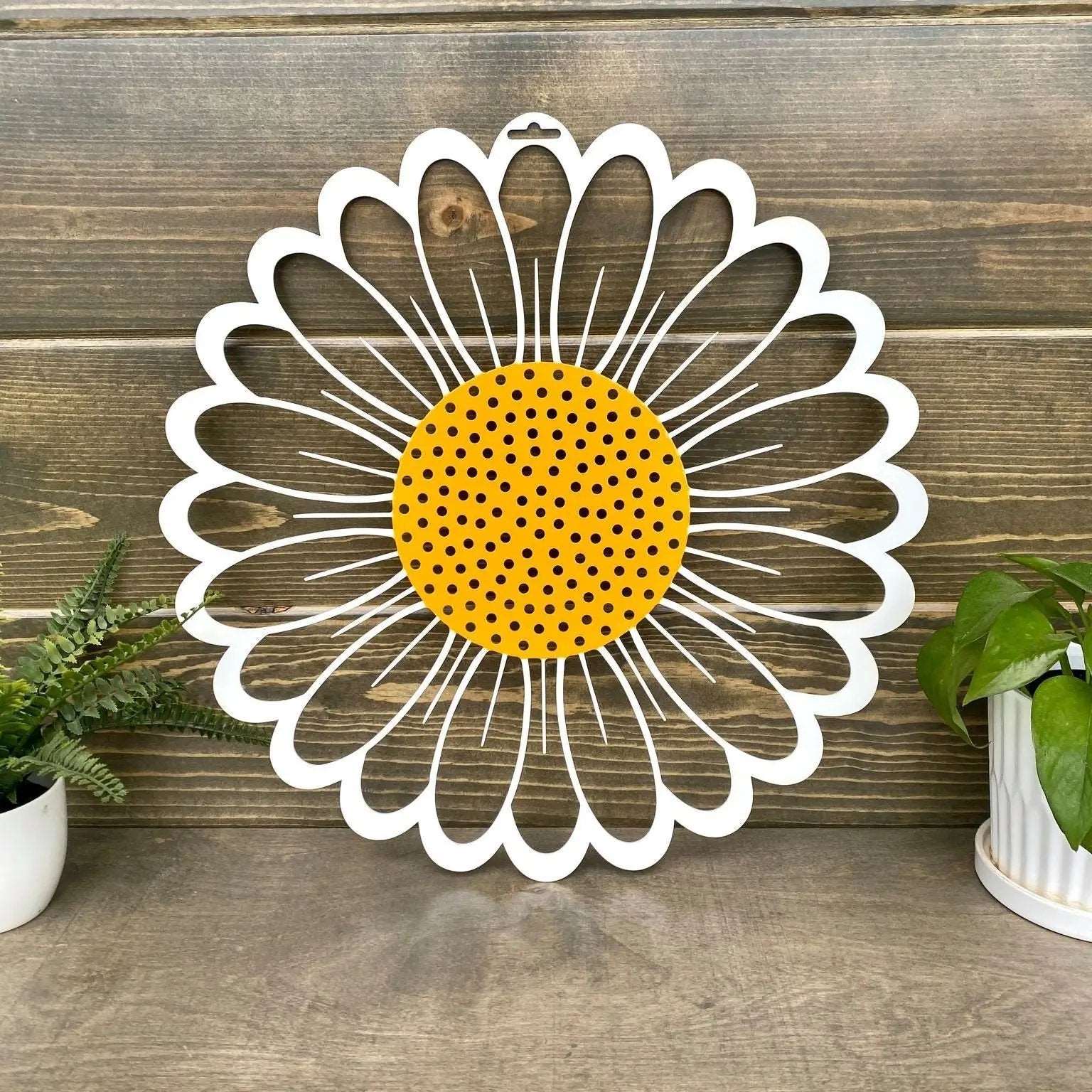Decorative metal wall art of daisy with yellow center and white petals on wooden background, custom indoor or outdoor home décor accent