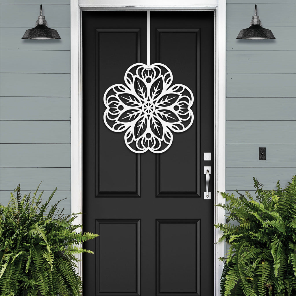 White floral mandala metal wall art on black front door, gray exterior wall with green plants, custom powder coated farmhouse entry décor, elegant welcome sign design