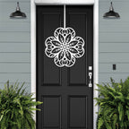 White floral mandala metal wall art on black front door, gray exterior wall with green plants, custom powder coated farmhouse entry décor, elegant welcome sign design