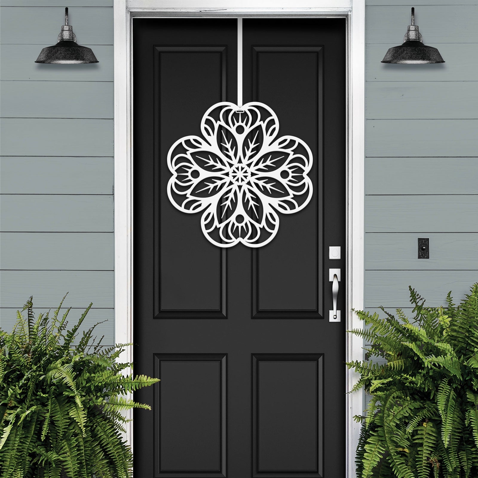 White floral mandala metal wall art on black front door, gray exterior wall with green plants, custom powder coated farmhouse entry décor, elegant welcome sign design