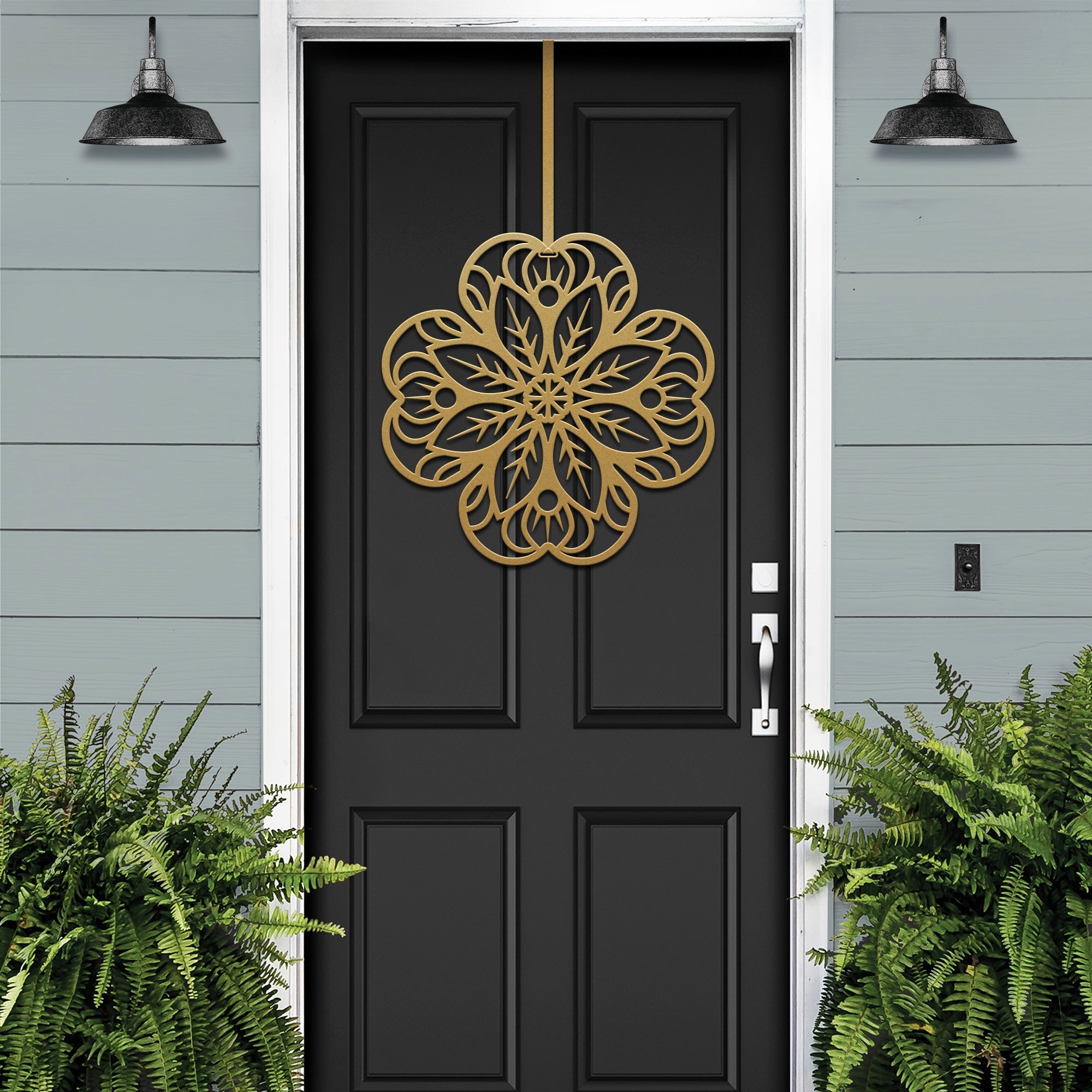 Black front door with gold floral mandala metal door hanger, light blue wall and green plants, custom powder coated farmhouse entry décor, elegant welcome sign design