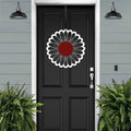 Black front door with circular floral wreath design, white and red metal accent décor, modern farmhouse entryway, curb appeal exterior home styling, custom metal wall art inspiration