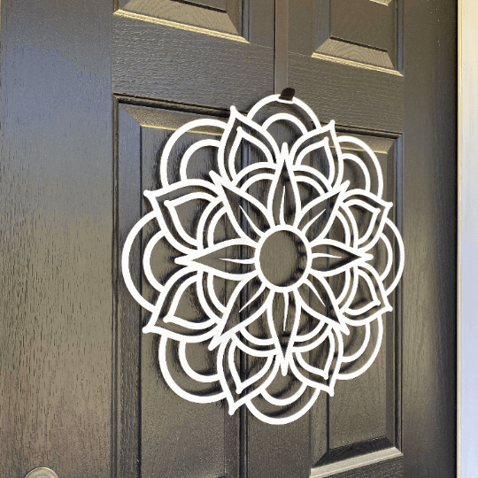 Side view white metal flower wreath on dark wood door, floral wall decor, handcrafted outdoor metal sign, modern entryway design