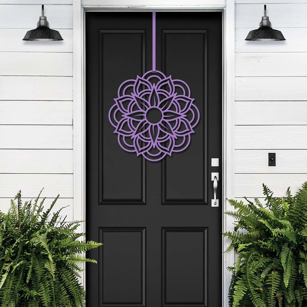 Lavender metal flower wreath on black door, purple floral decor, green plants, white wall exterior, handcrafted outdoor metal sign, elegant entryway art