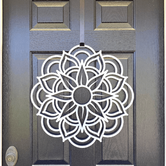 Close-up white mandala metal flower wreath on dark gray door, modern floral wall decor, handcrafted outdoor metal sign, elegant entryway design
