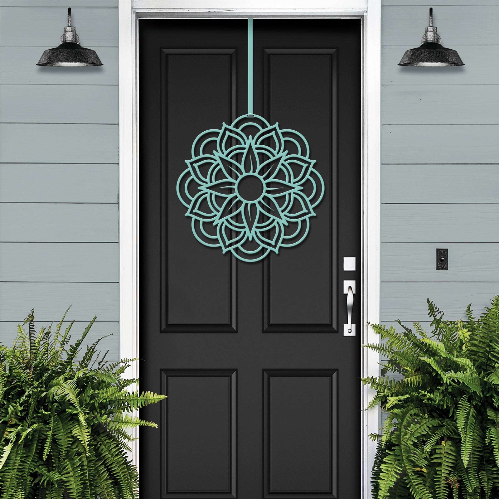 Handcrafted metal flower wreath on black door, green botanical pattern, gray exterior wall, modern outdoor metal decor, custom powder coated sign
