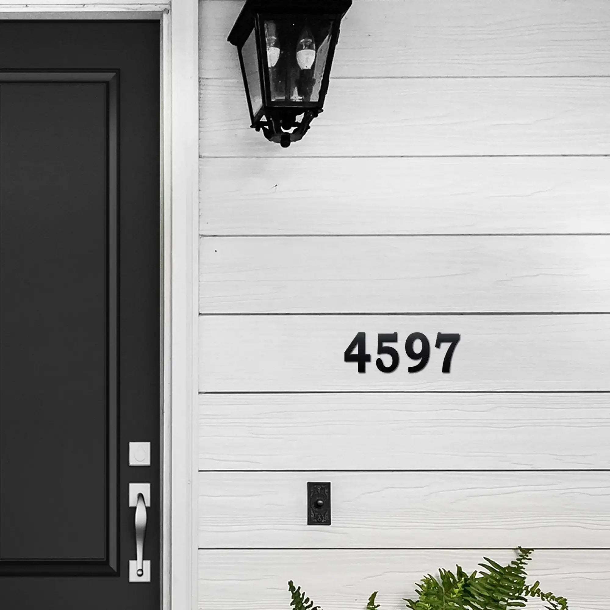 House exterior with black door, wall light fixture, and house number 4597, modern home façade with outdoor address signage