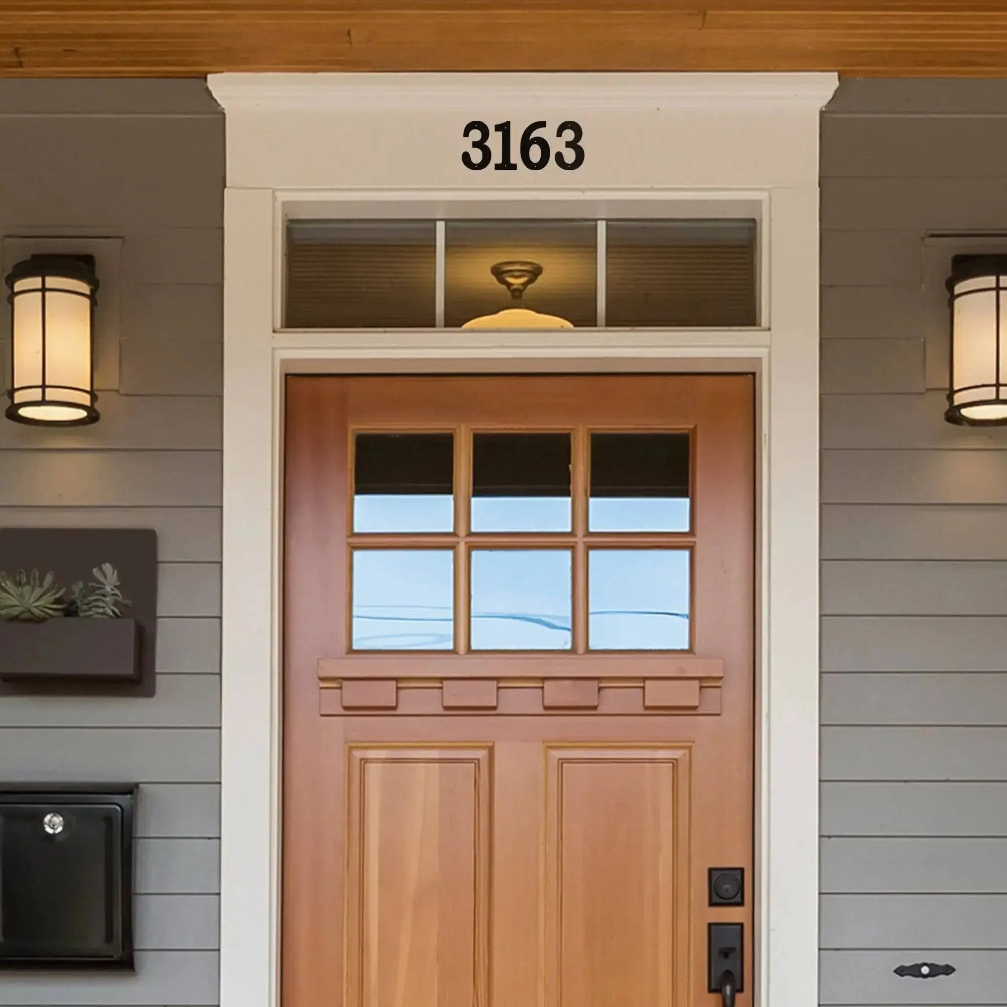 Wooden front door with glass panels and house number 3163 on gray siding, modern outdoor address signage, decorative home exterior house numbers