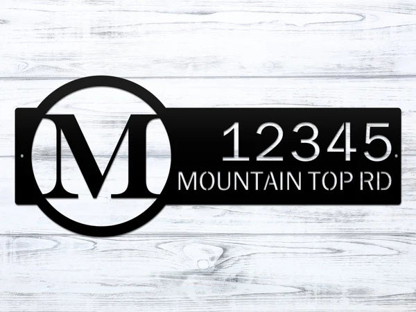 Close-up black metal monogram sign with letter 'M' and '12345 Mountain Top RD'.