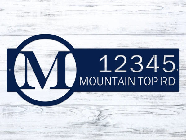 Close-up navy blue metal monogram sign with letter 'M' and '12345 Mountain Top RD'.