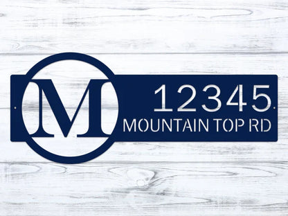 Close-up navy blue metal monogram sign with letter 'M' and '12345 Mountain Top RD'.