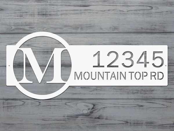 Close-up white metal monogram sign with letter 'M' and '12345 Mountain Top RD'.
