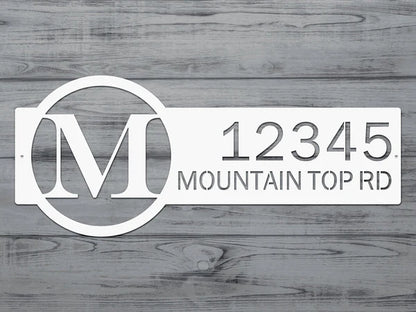 Close-up white metal monogram sign with letter 'M' and '12345 Mountain Top RD'.