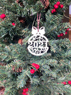 Decorative Christmas ornament displaying “2021” hanging on a tree, surrounded by green branches with red berries and pinecones, creating a festive and traditional holiday scene.