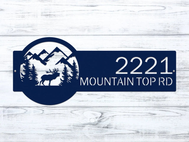 Close-up of navy blue Mountain Elk Address Sign featuring elk, pine trees, and mountain on the right, with house number '2221 Mountain Top Rd' on the left.