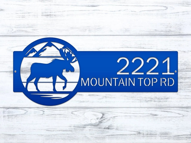 Close-up of bright blue Mountain Moose Address Sign with moose and mountain on right and house number '2221 Mountain Top Rd'.