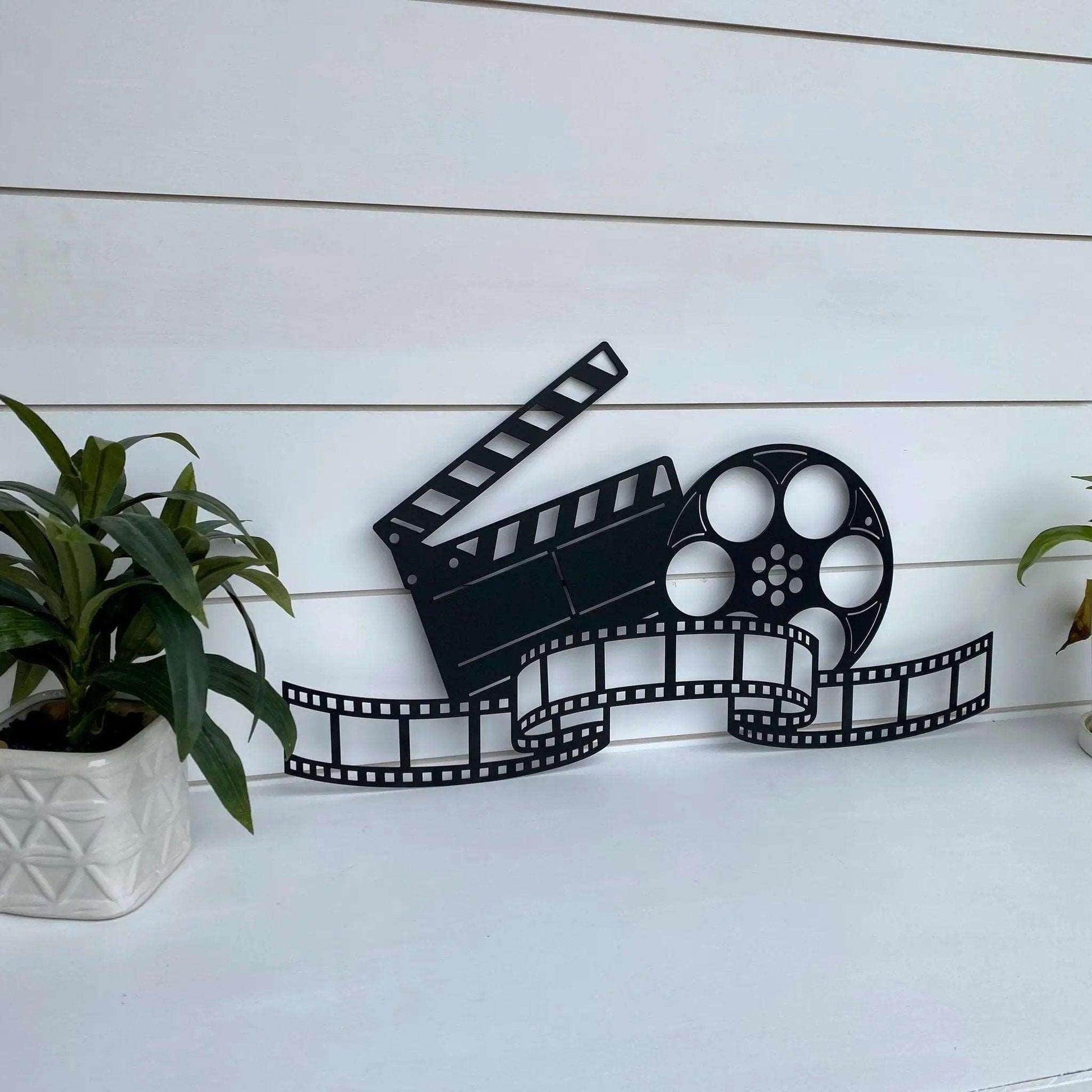 Movie-themed metal decor with reel, film strip, and clapboard silhouettes stylish wall accent for entertainment rooms.