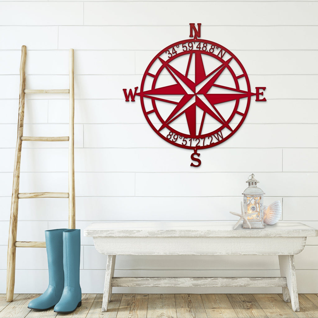 Red nautical compass rose metal wall décor on white wall with wooden ladder and table in foreground, coastal-inspired décor, HouseSensationsArt