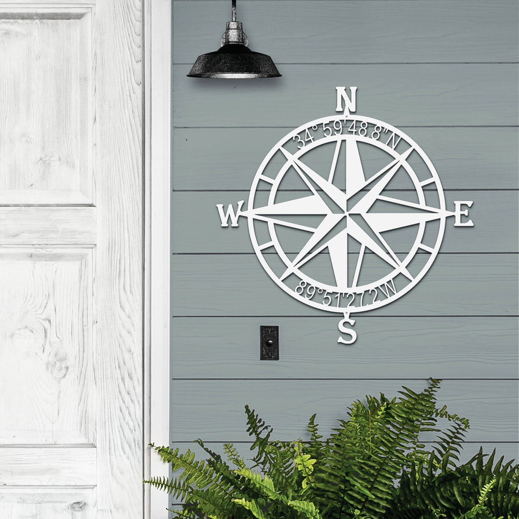 Decorative nautical compass rose metal wall art on gray wooden wall with greenery at the bottom, coastal-themed décor, HouseSensationsArt