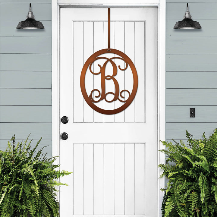Brown oval metal monogram door wreath shown on a white door