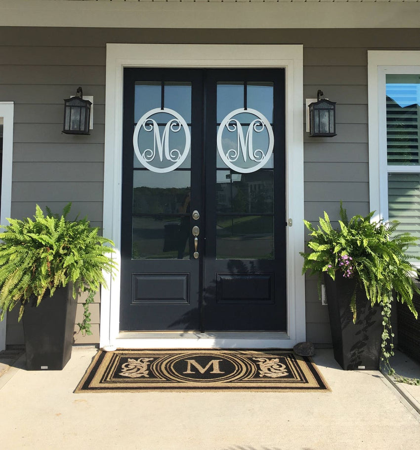 White oval metal monogram door wreath shown on a black door