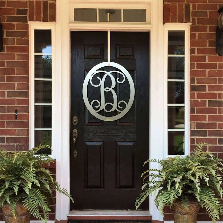 Silver oval metal monogram door wreath shown on a wood door