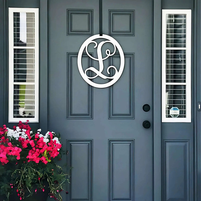 White oval metal monogram door wreath shown on a grey door
