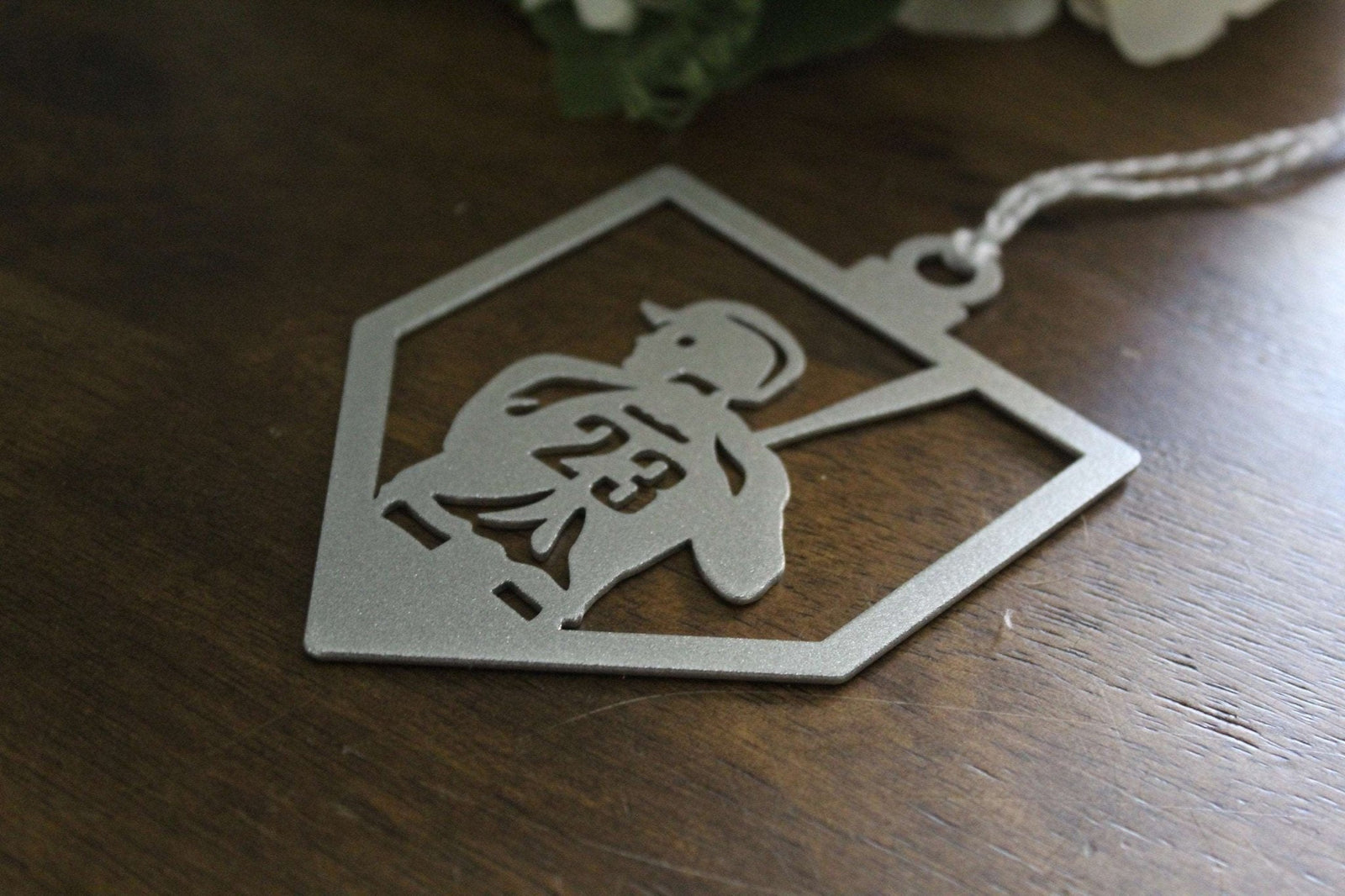 Decorative metal tag with cut-out design placed on wooden surface, custom laser-cut metal décor for personalized signage, gifts, or craft projects