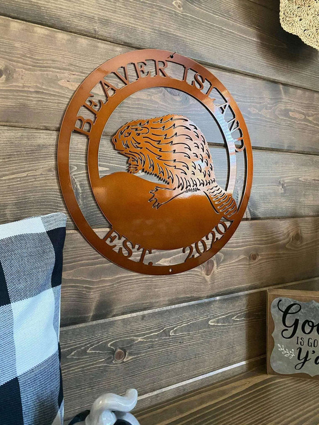 Closer shot candy copper laser cut ranch sign with beaver silhouette, “BEAVER ISLAND EST 2020” text; rustic decor.