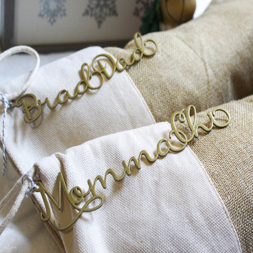 Decorative gold Bread Doll and Momma signs displayed on textured fabric background, personalized metal décor for home display or gift purposes