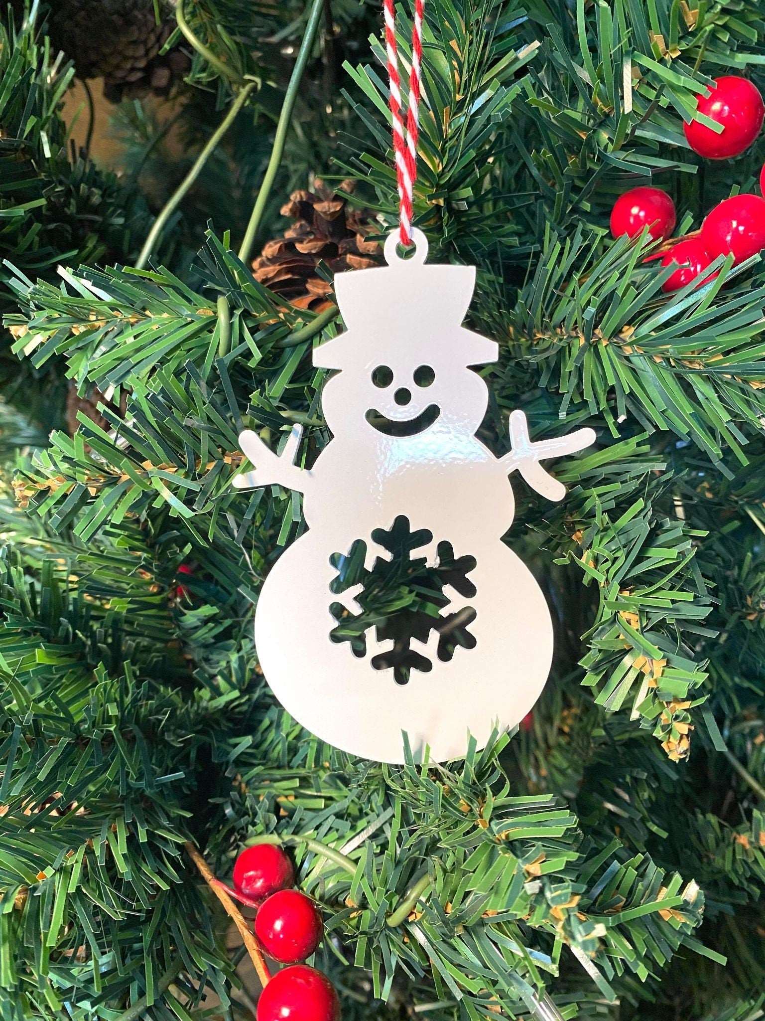 White snowman ornament hanging on Christmas tree with red berries, festive holiday decoration for seasonal décor and Christmas tree display