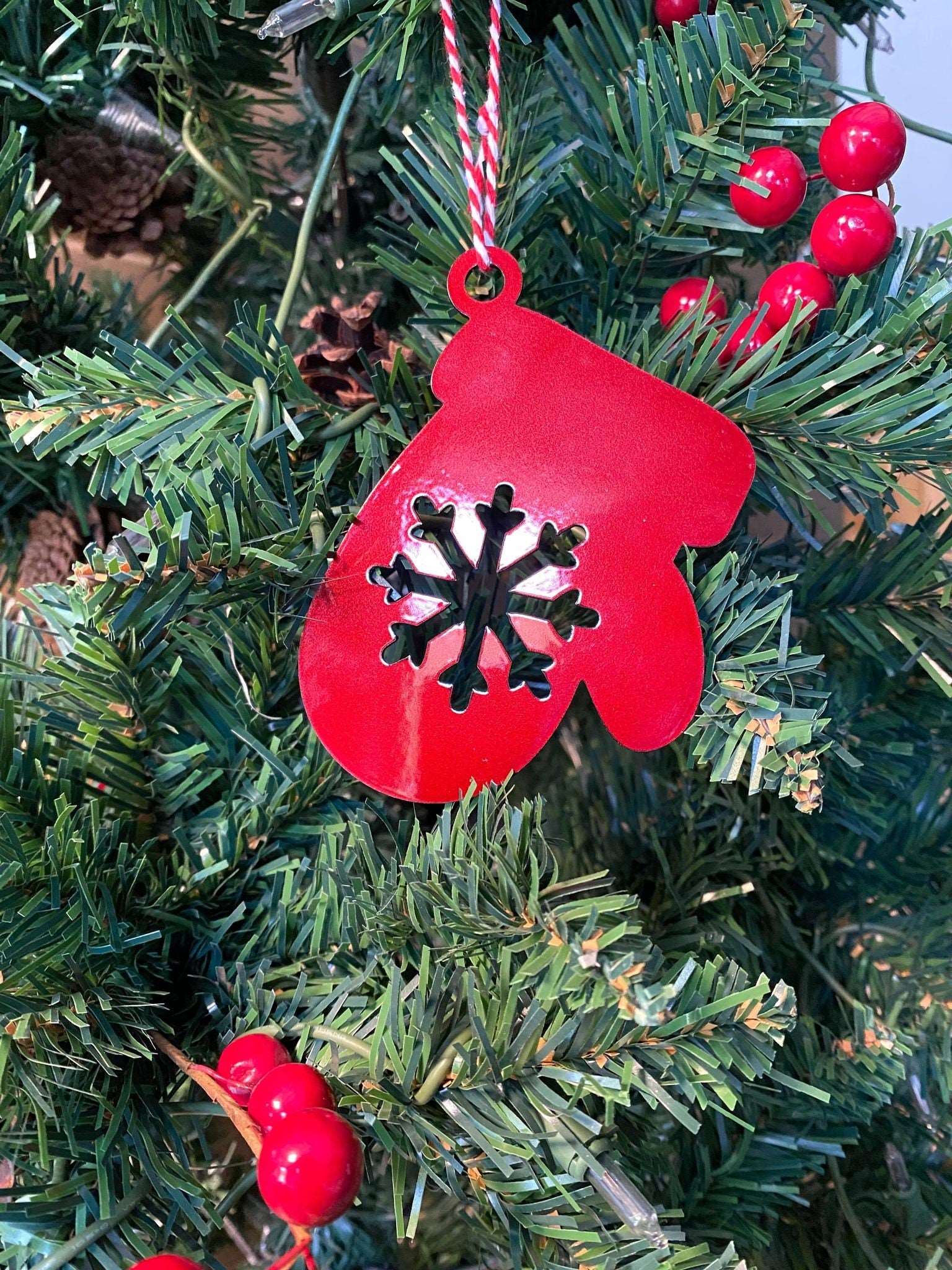 Red mitten ornament with snowflake design hanging on Christmas tree, festive holiday decoration for seasonal décor and Christmas tree display