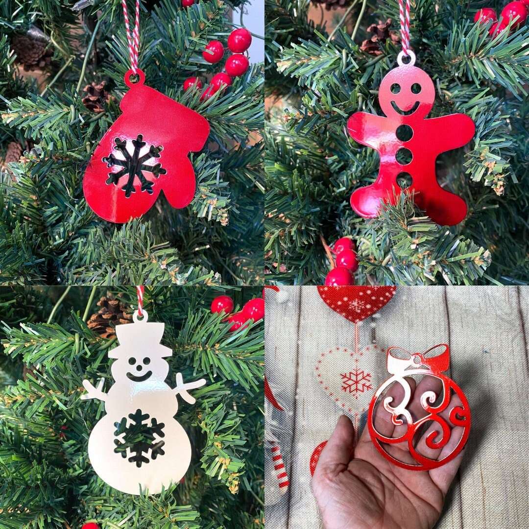 Set of red Christmas tree ornaments including mitten, gingerbread man, snowman, and ball hanging on green tree, festive holiday decorations for seasonal décor