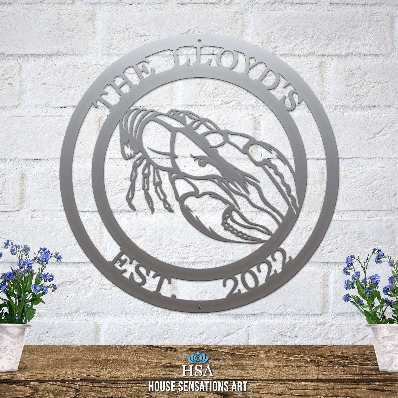 A polished chrome custom laser cut metal sign showing crawfish in center, with “THE LLYOD’S EST 2022” text, outdoor nautical decor.