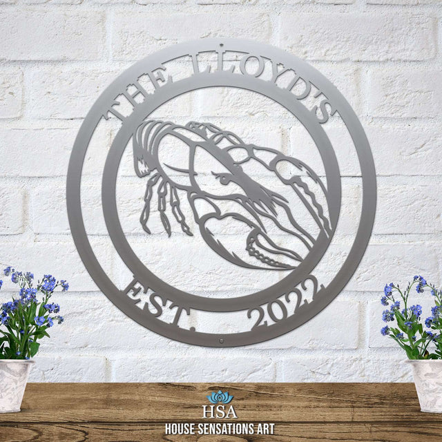 A polished chrome custom laser cut metal sign showing crawfish in center, with “THE LLYOD’S EST 2022” text, outdoor nautical decor.