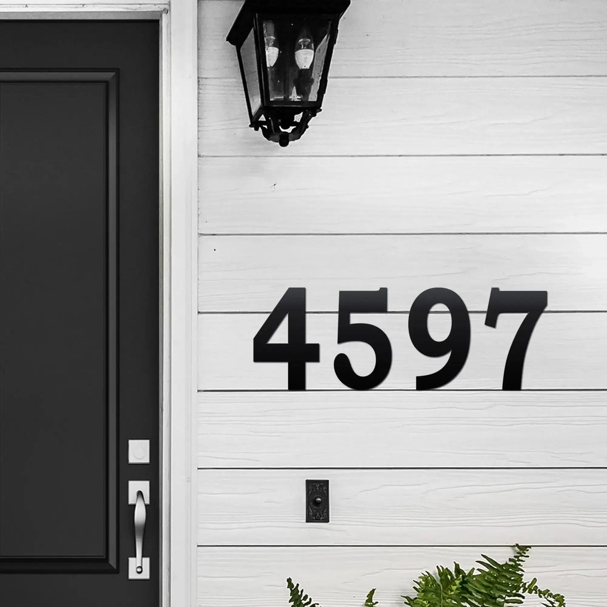 House number “4597” displayed on a white wooden door with a black lantern for outdoor address décor