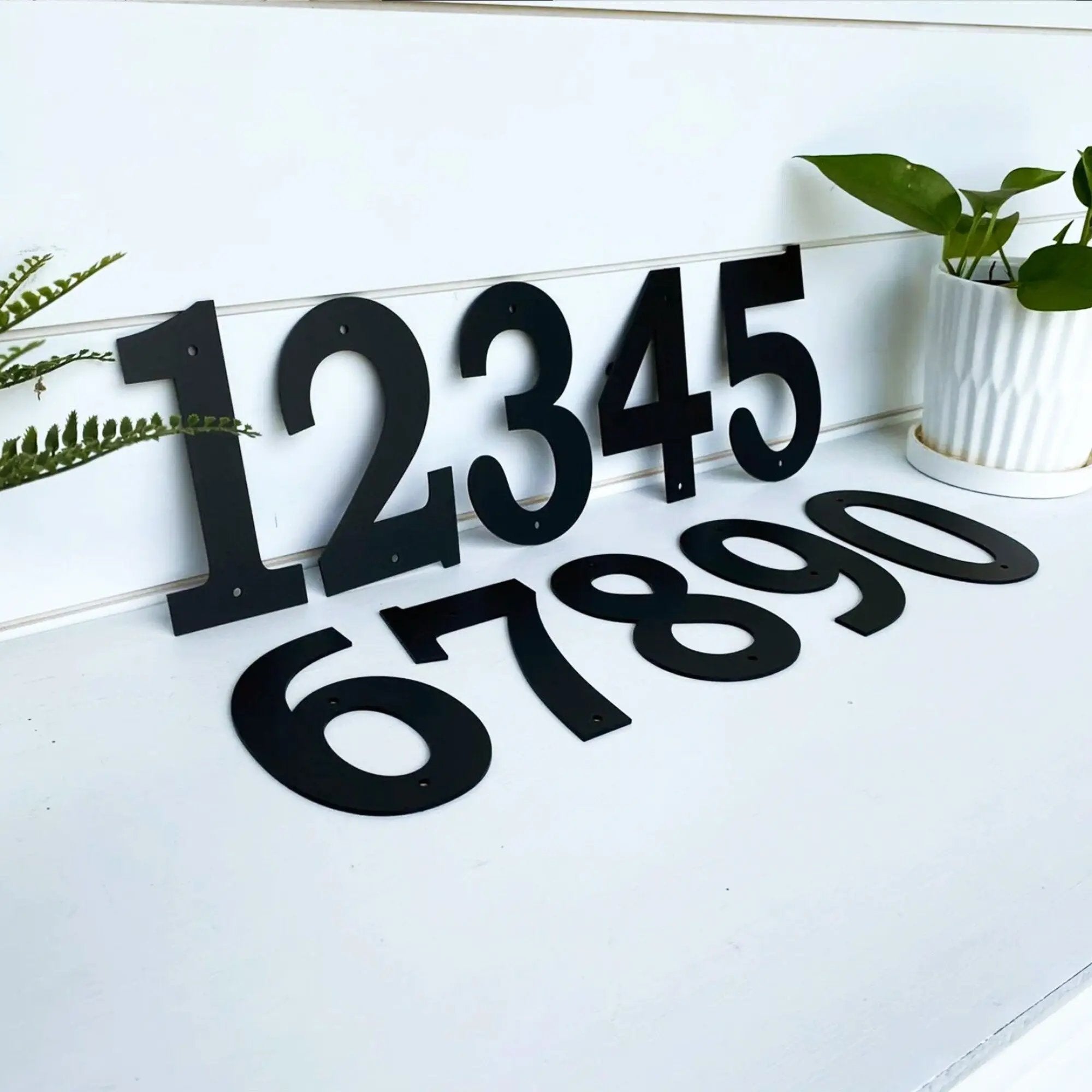 Black house numbers “1234567890” on white wooden surface for custom outdoor address signs, personalized home curb appeal, and decorative front door number display