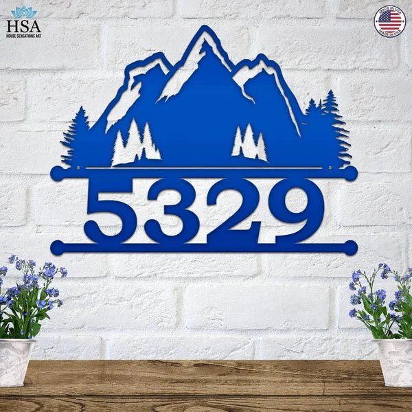 Blue personalized metal house number sign with mountain design mounted on a white brick wall for outdoor curb appeal, HouseSensationsArt